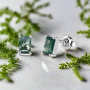 Silver earrings with green gemstones on a white background