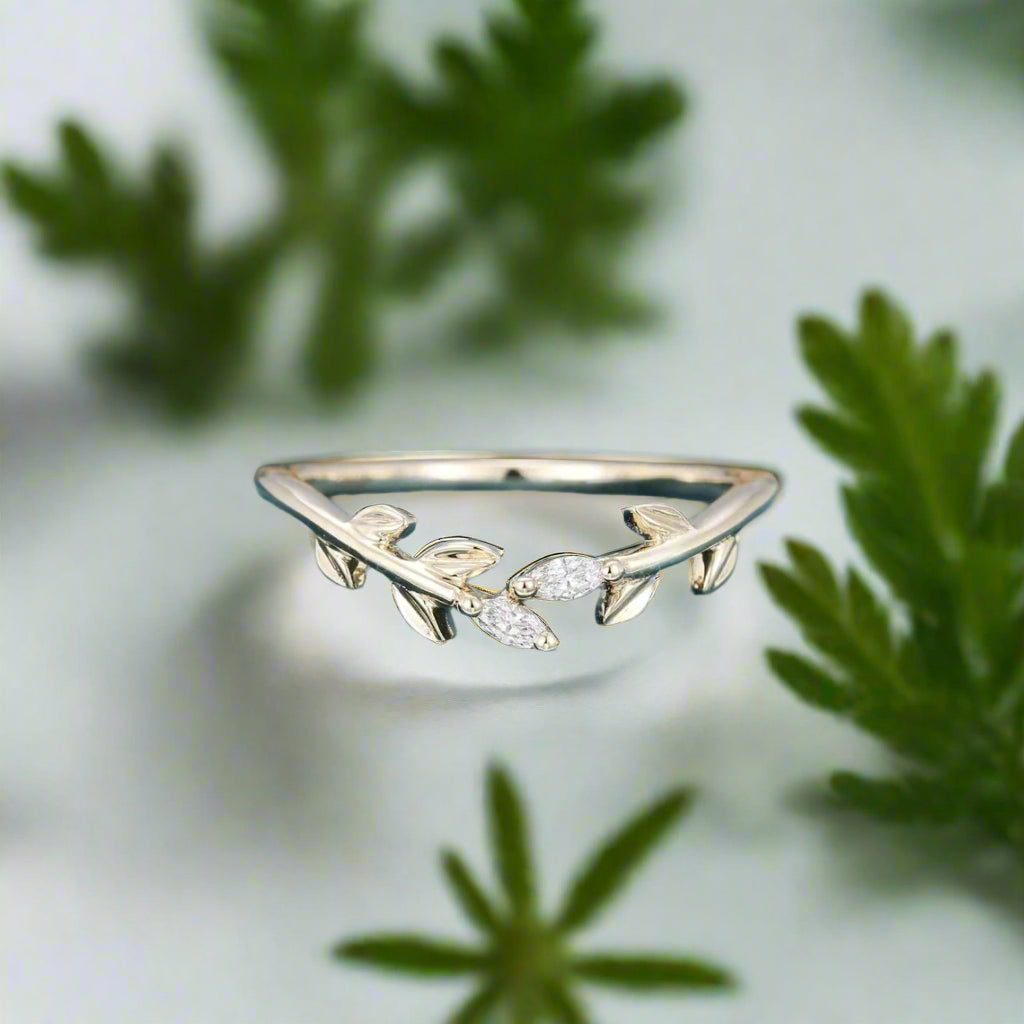 Silver leaf-shaped ring on a blue surface with a blurred natural background