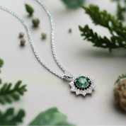 Silver necklace with a green gemstone pendant on a light blue background