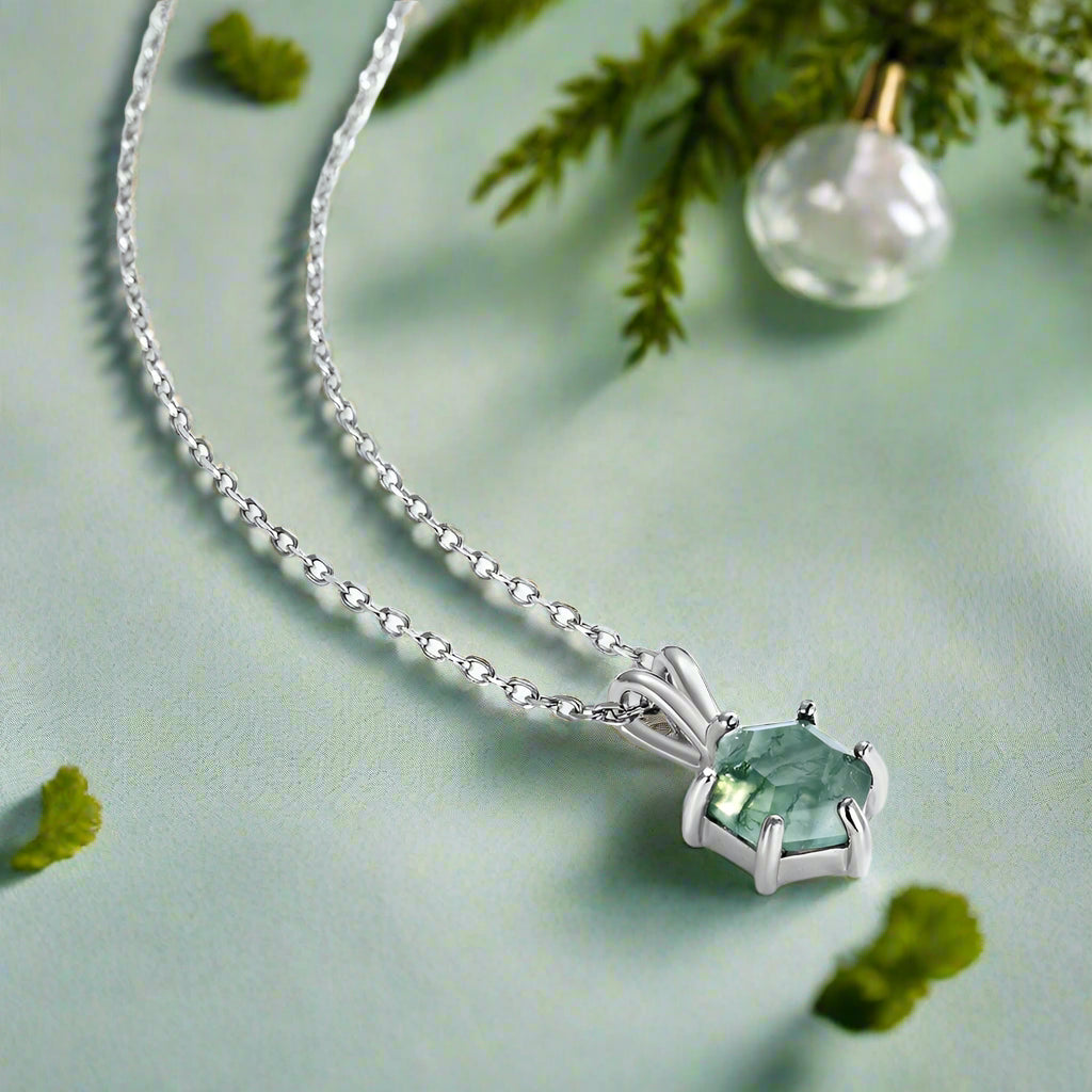 Silver necklace with a green gemstone pendant on a white background