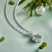 Silver necklace with a green gemstone pendant on a white background
