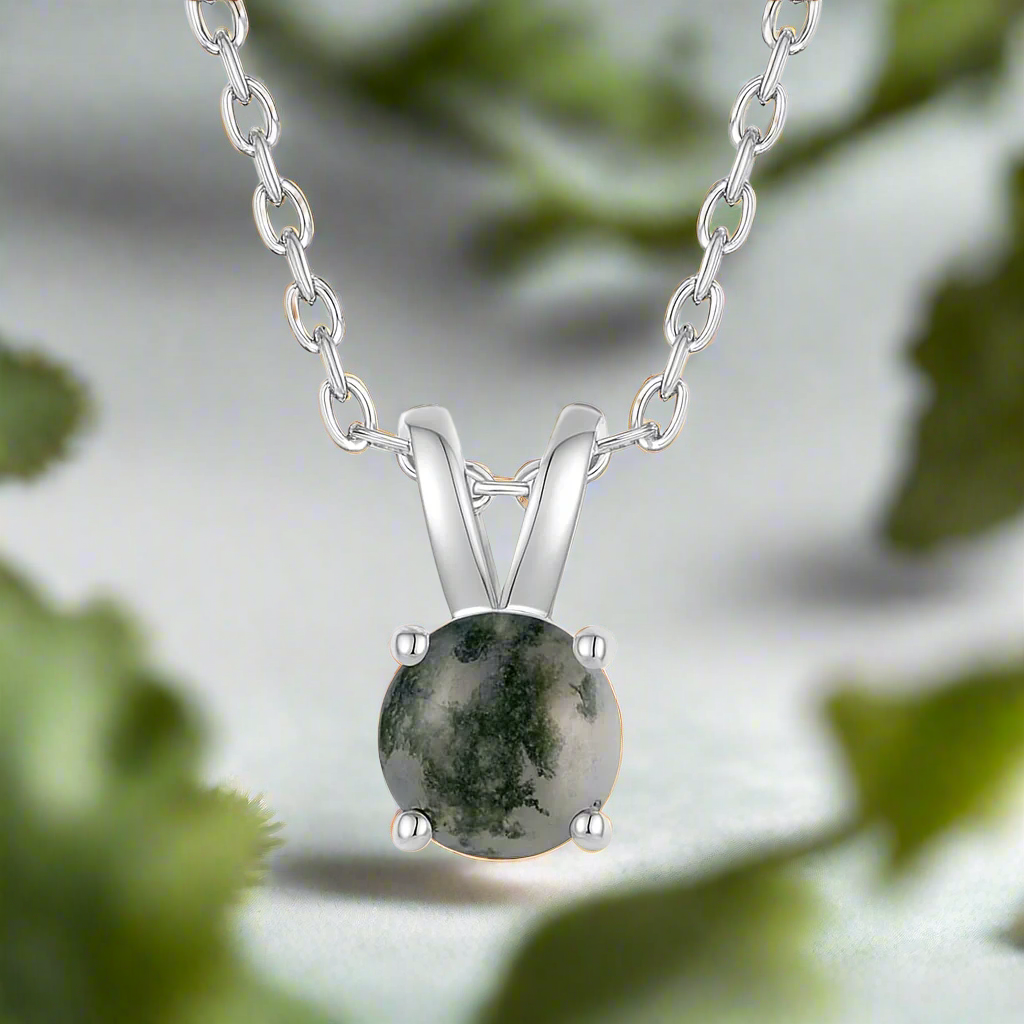 Silver necklace with a green stone pendant on a white background
