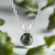 Silver necklace with a green stone pendant on a white background