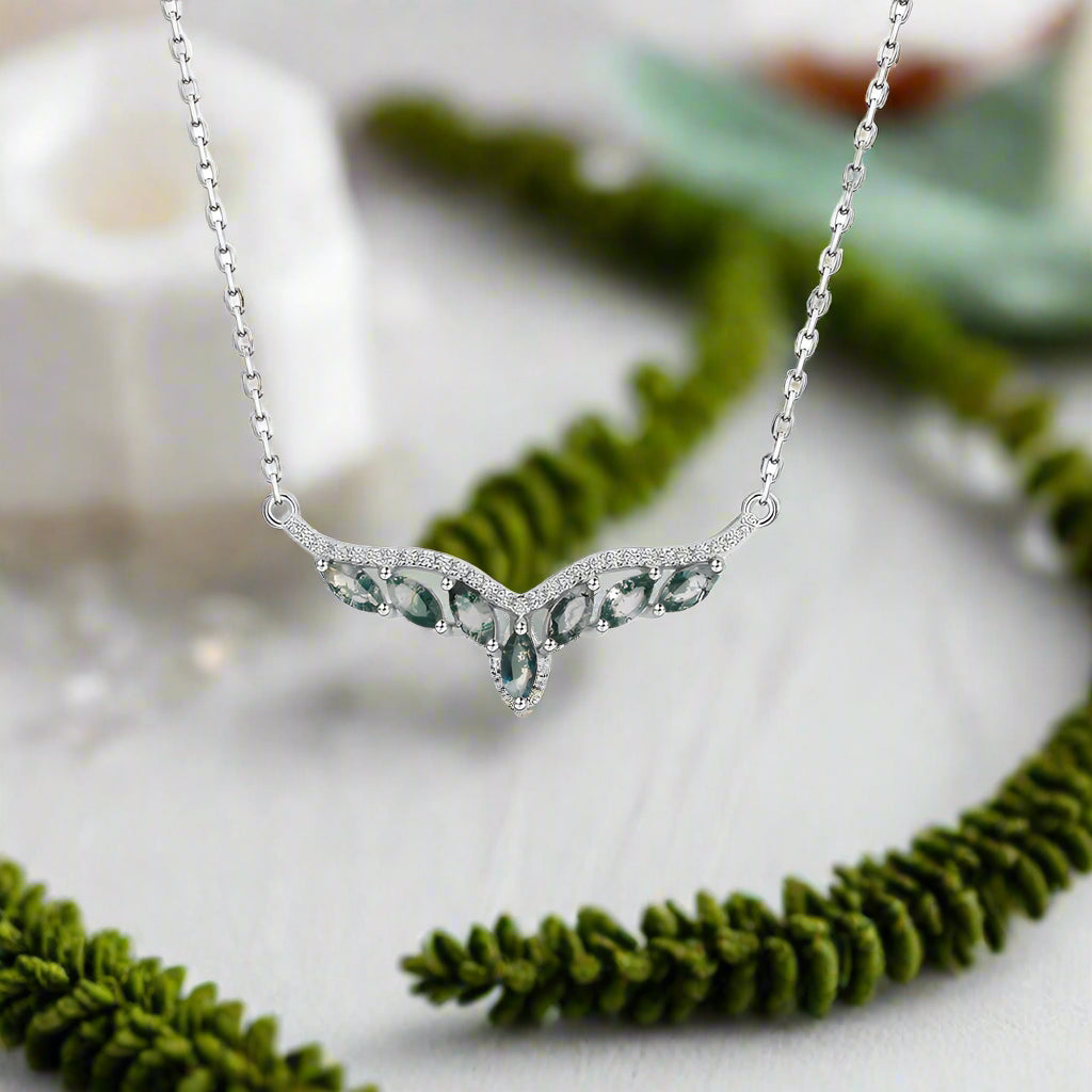 Silver necklace with green gemstones on a white background