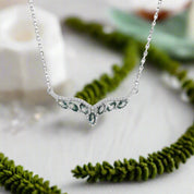 Silver necklace with green gemstones on a white background