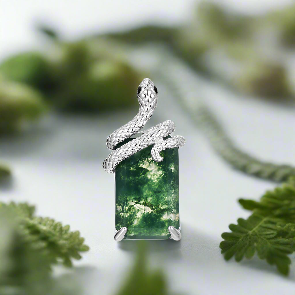 Silver pendant with a green forest scene on a white background