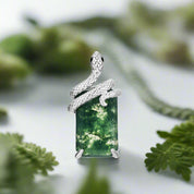 Silver pendant with a green forest scene on a white background