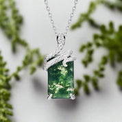 Silver pendant with a green forest scene on a white background