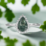 Silver ring with a green gemstone and diamond accents on a white background