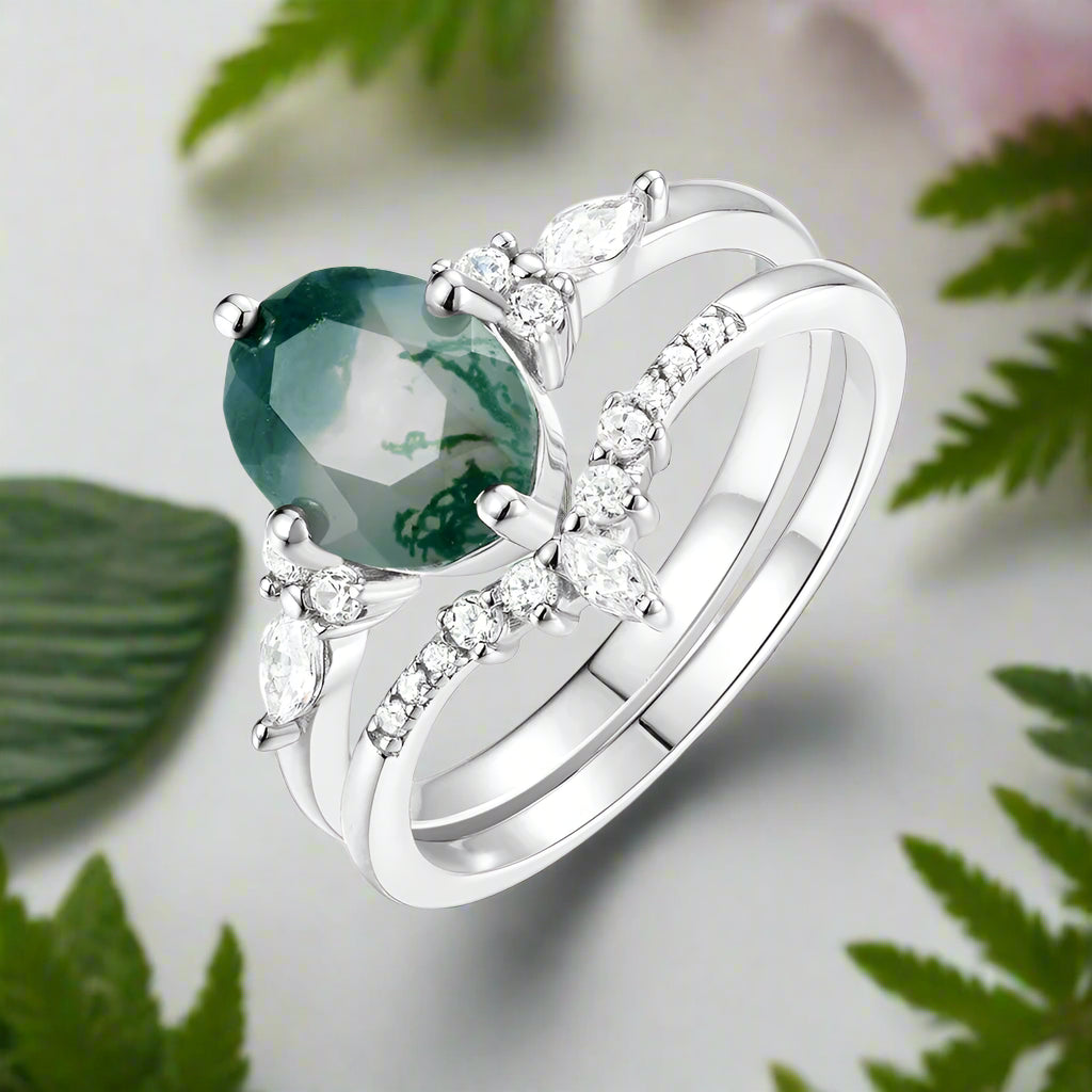 Silver ring with a green gemstone and diamonds on a white background