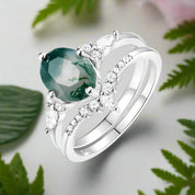 Silver ring with a green gemstone and diamonds on a white background