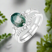 Silver ring with a green gemstone and diamonds on a white background