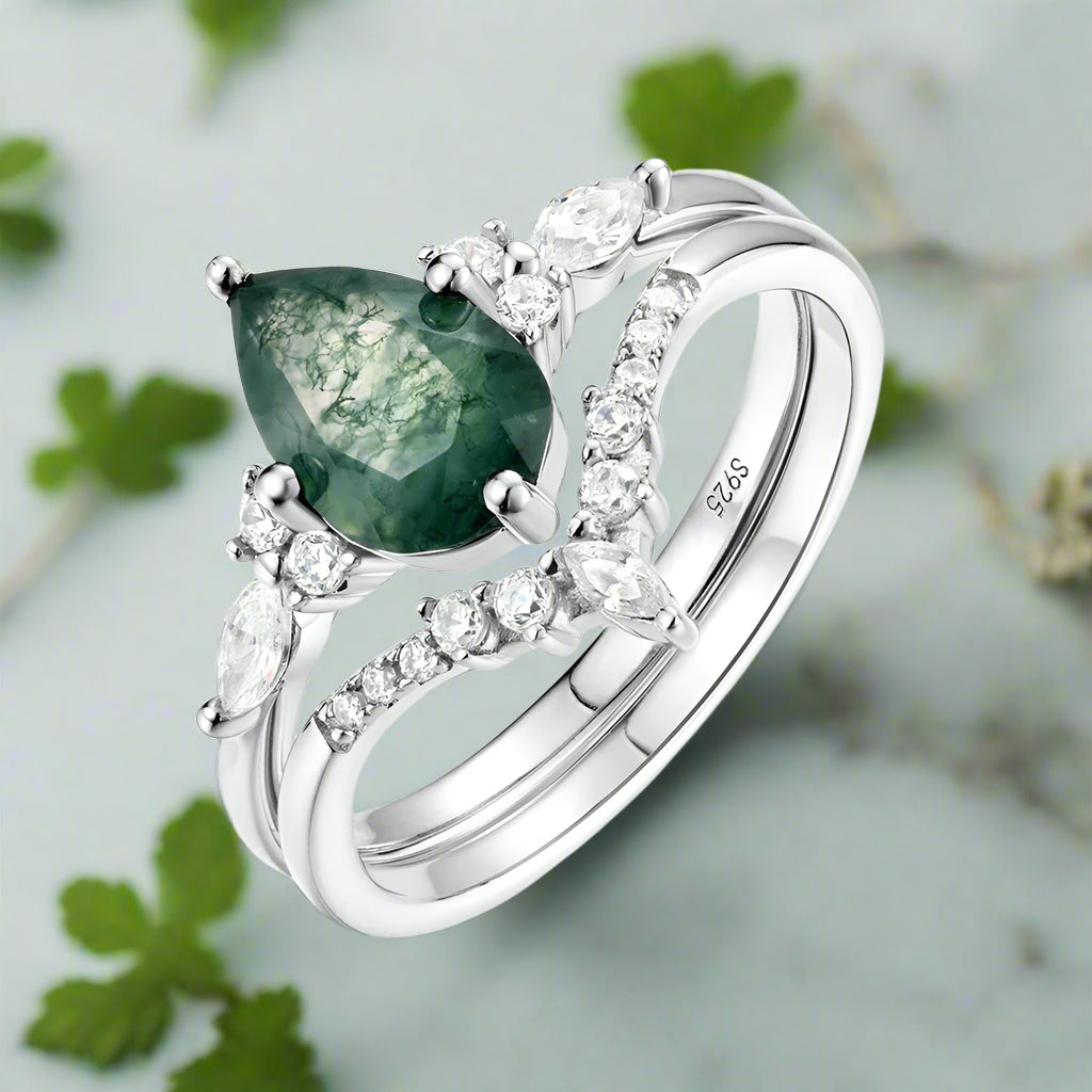 Silver ring with a green gemstone and diamonds on a white background