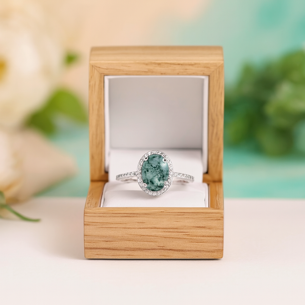 Silver ring with a green gemstone in a wooden box on a light background