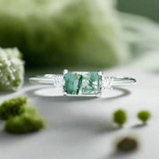 Silver ring with a green gemstone on a light blue background