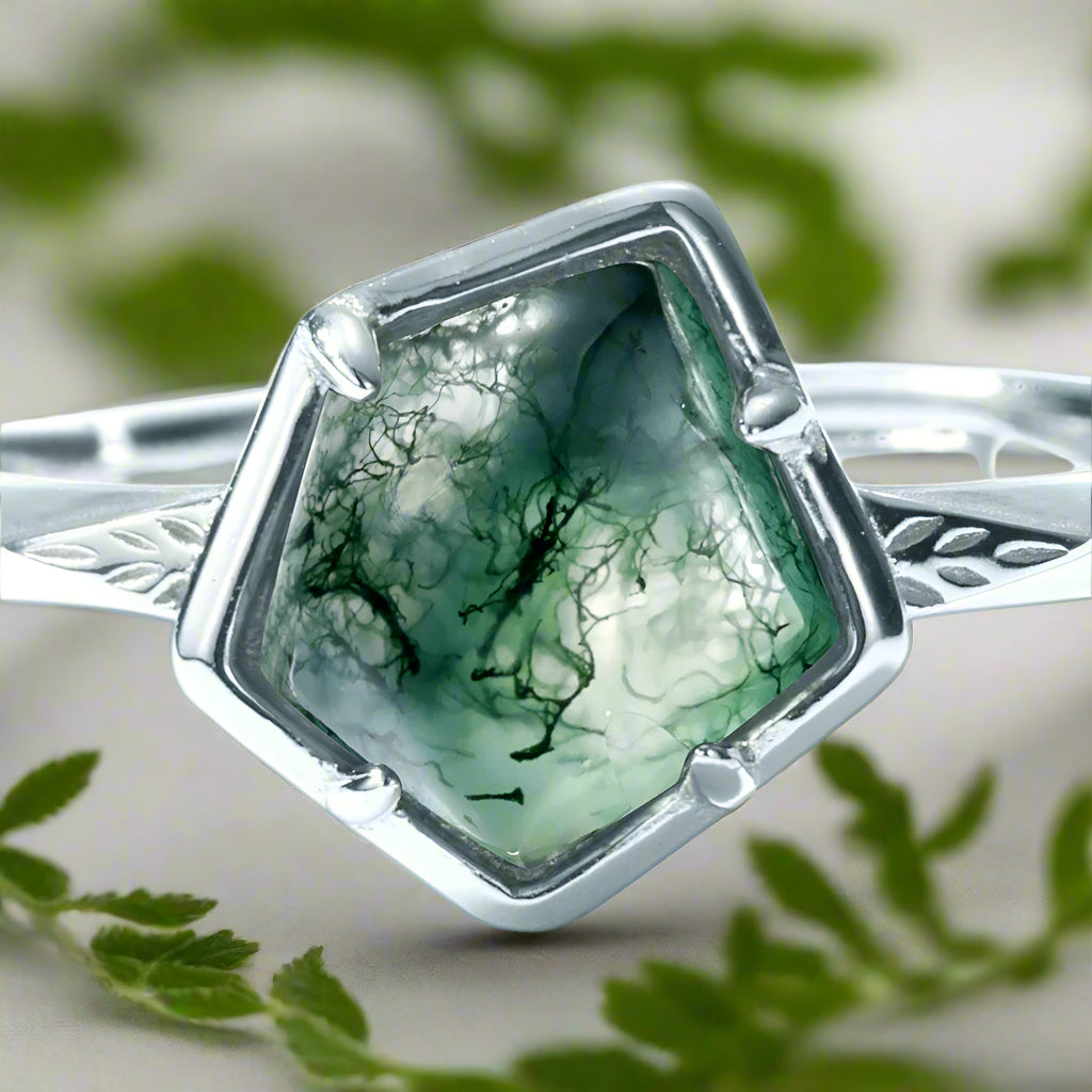 Silver ring with a green gemstone on a white background