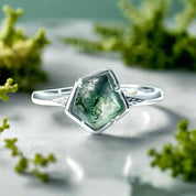 Silver ring with a green gemstone on a white background