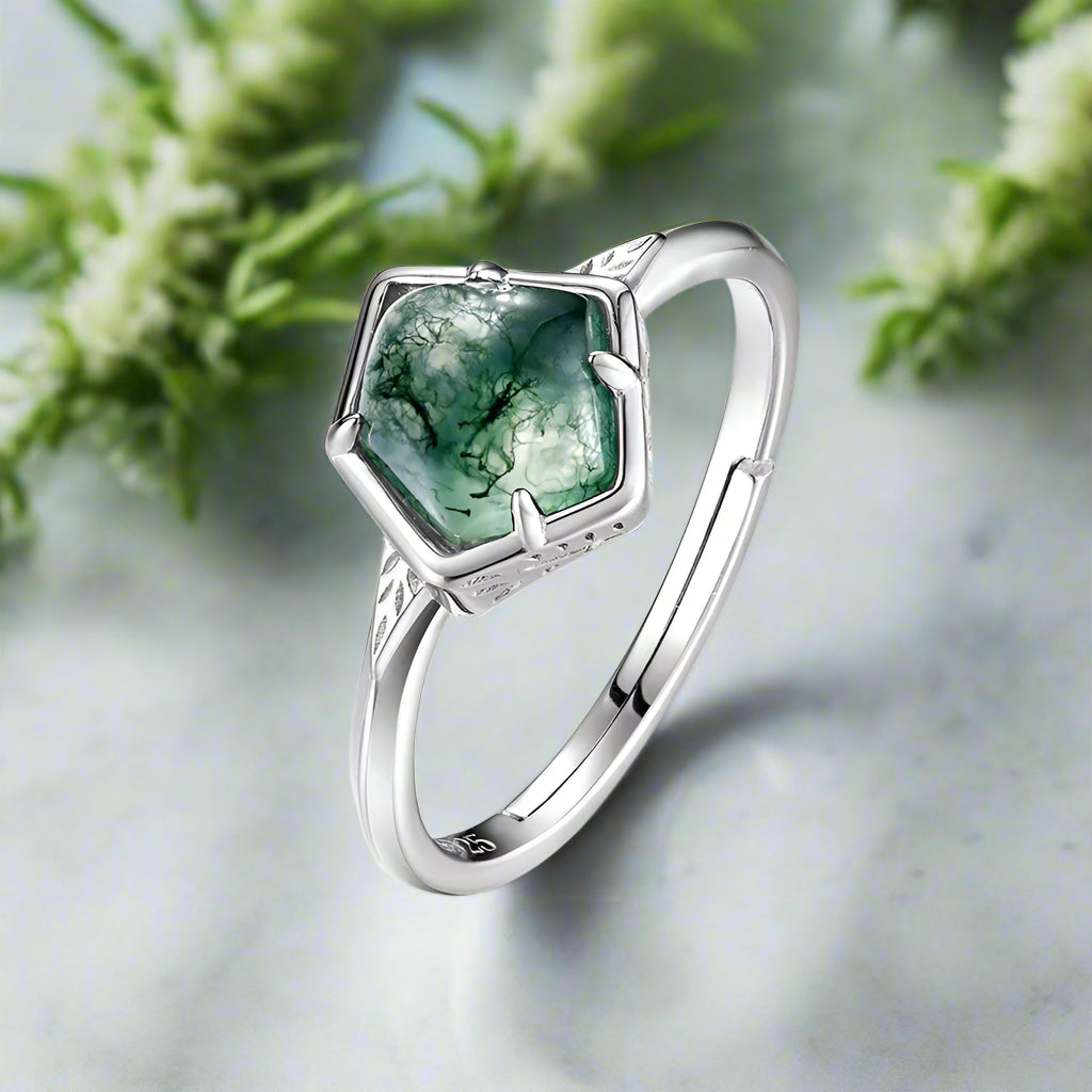 Silver ring with a green gemstone on a white background
