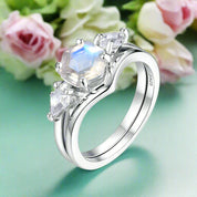 Silver ring with a large central gemstone and smaller side stones on a white background