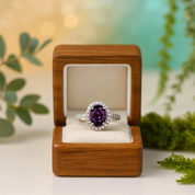 Silver ring with a purple gemstone in a wooden box with a blurred greenery background