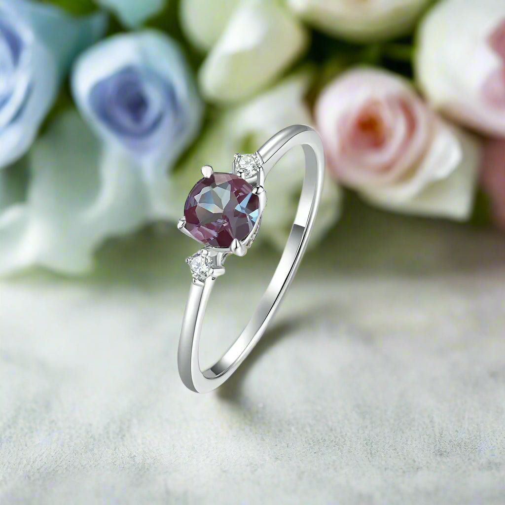 Silver ring with a purple gemstone on a soft pink floral background