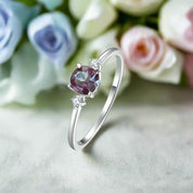 Silver ring with a purple gemstone on a soft pink floral background