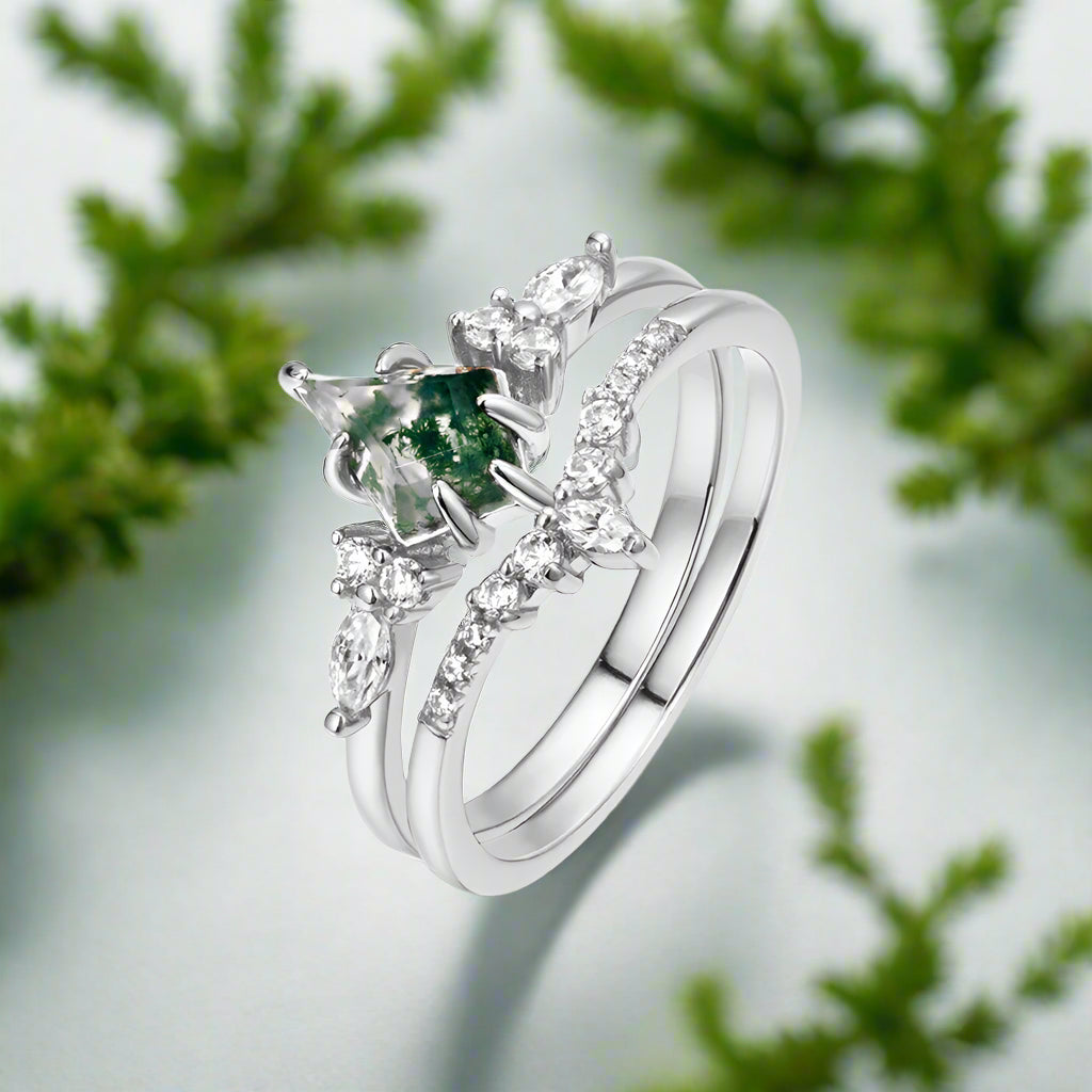 Silver ring with green gemstone and clear stones on a white background