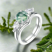 Silver ring with green gemstone and clear stones on a white background