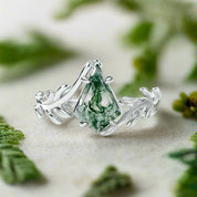 Silver ring with green gemstone on a light blue background