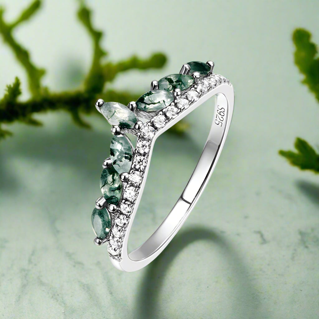 Silver ring with green gemstones on a white background