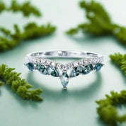 Silver ring with green gemstones on a white background
