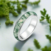 Silver ring with green marbled inlay on a white background