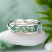 Silver ring with green marbled pattern on a white background