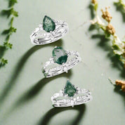 Three silver rings with green gemstones on a white background