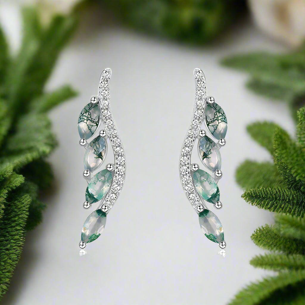 Pair of silver earrings with green gemstones on a white background