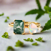 Two gold rings with green and pink gemstones on a white background