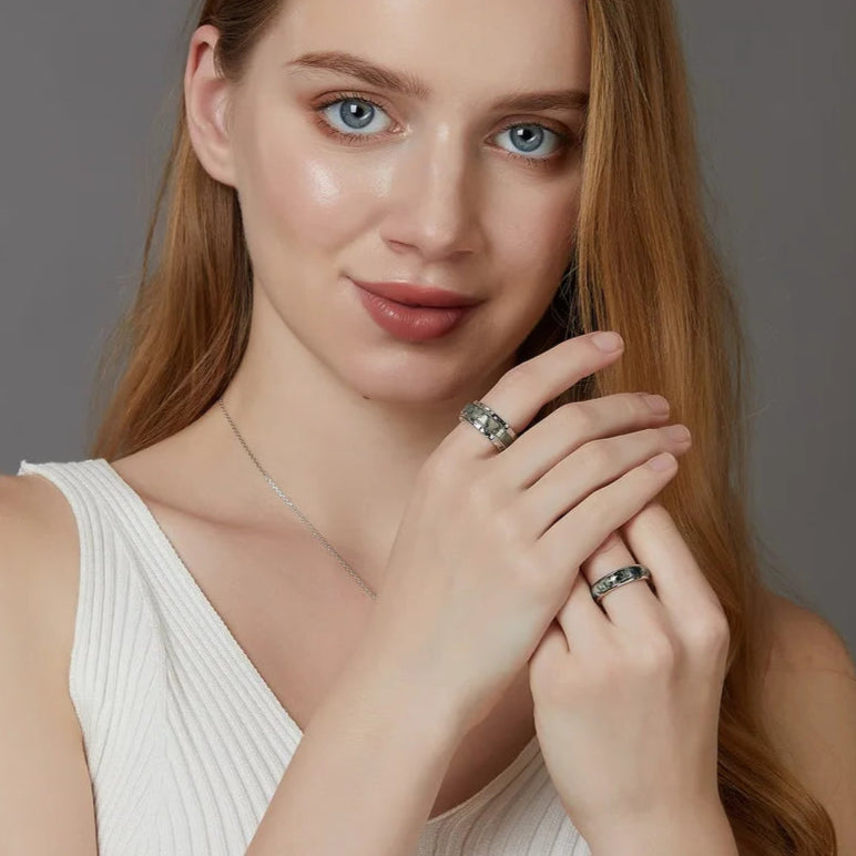Woman wearing a silver ring on her finger against a gray background