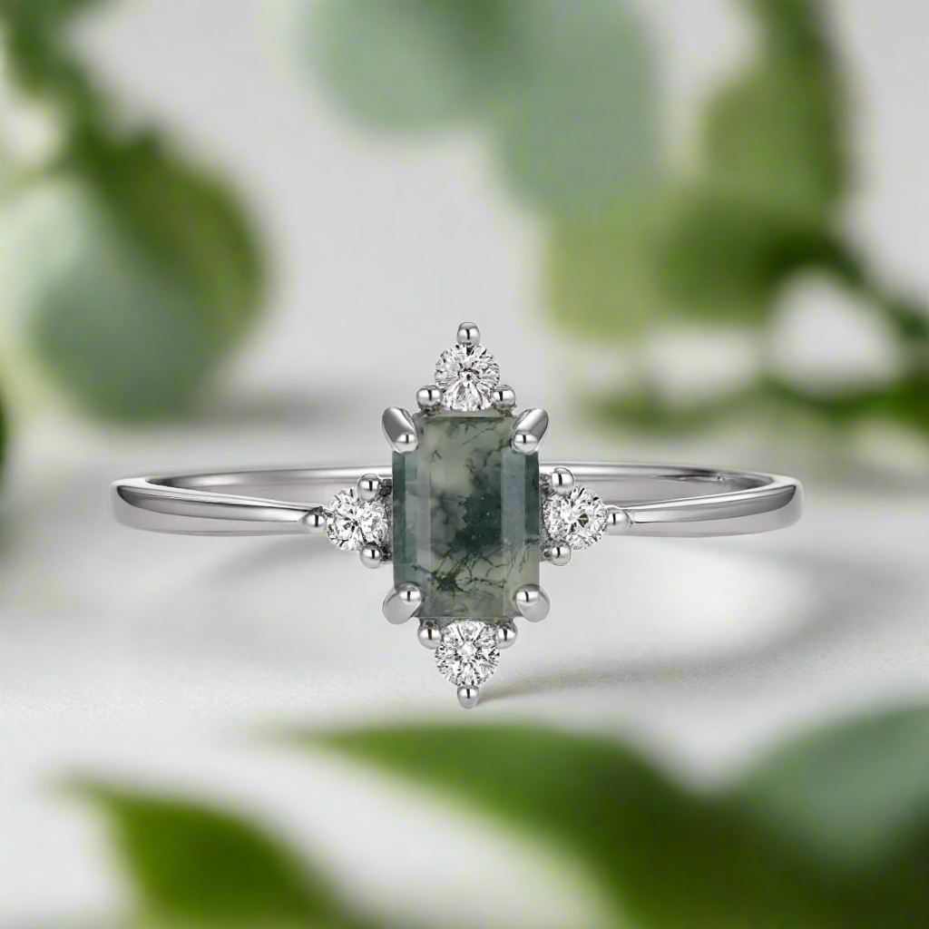 Silver ring with a green gemstone and diamonds on a white background