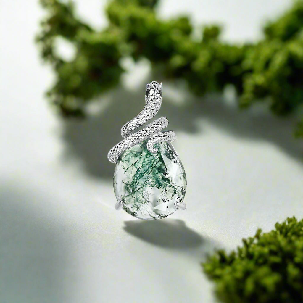 Silver pendant with a green stone on a white background