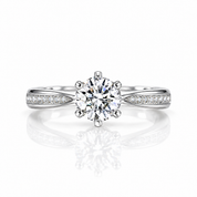 A classic solitaire engagement ring featuring a round brilliant-cut diamond center stone in a six-prong setting, with a split shank band paved with small round diamonds, shown on a reflective white surface.