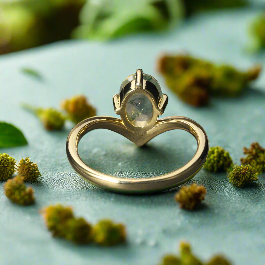 Gold ring with a green gemstone on a dark surface