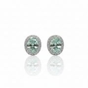 A pair of oval stud earrings featuring light green marquise-cut center stones surrounded by a halo of small clear stones in a silver-toned setting, displayed on a reflective white surface.