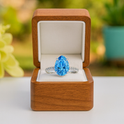 Blue gemstone ring in a wooden box with a blurred green background