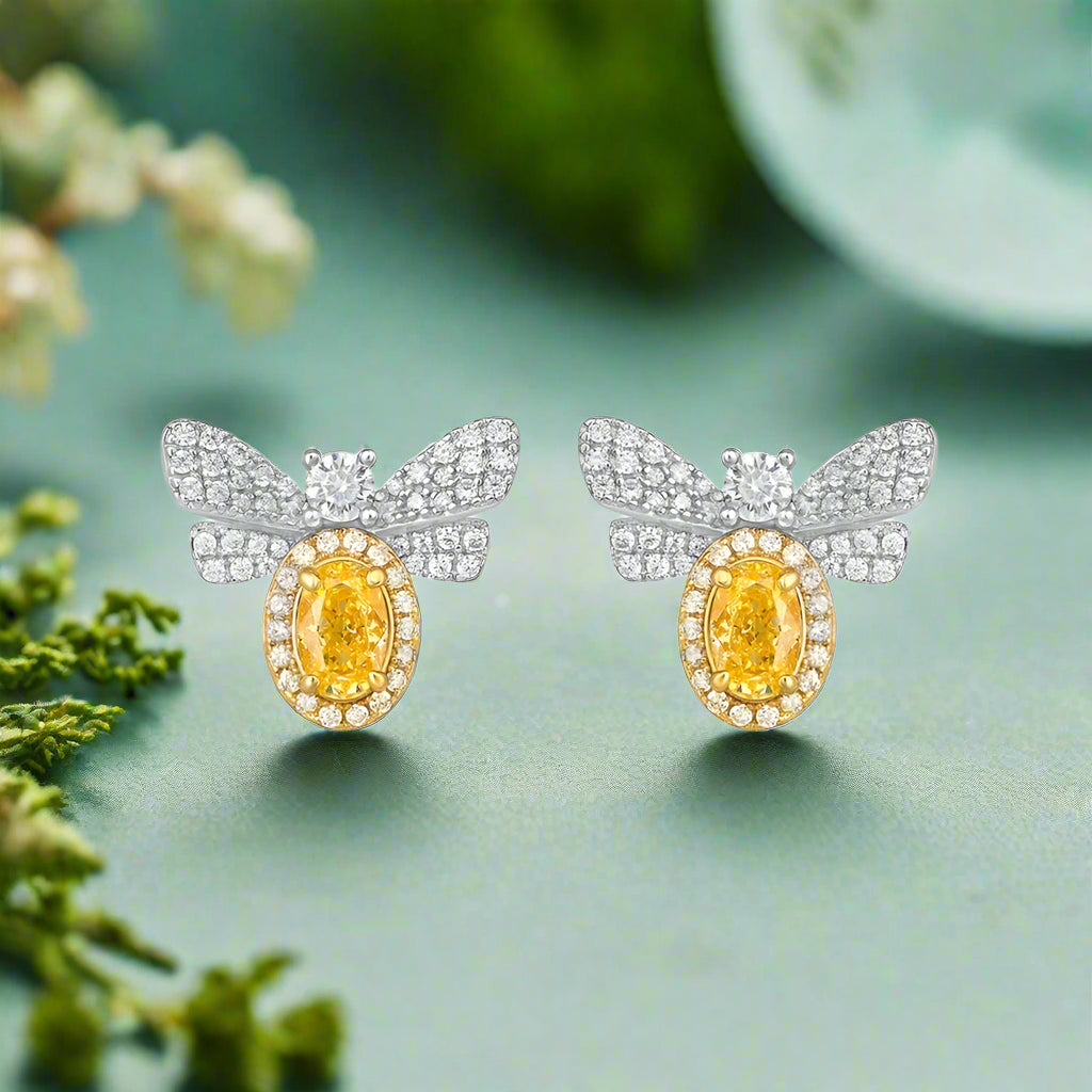 Butterfly-shaped earrings with yellow gemstones and diamond accents on a white background