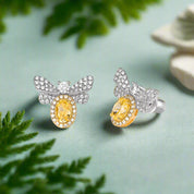 Butterfly-shaped earrings with yellow gemstones on a light gray background