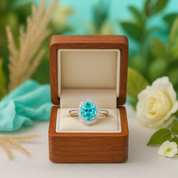 Ring with a blue gemstone in a wooden box with a floral background