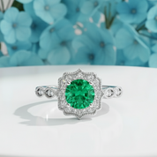 Close-up of a hand wearing a ring with a green gemstone on a blurred background