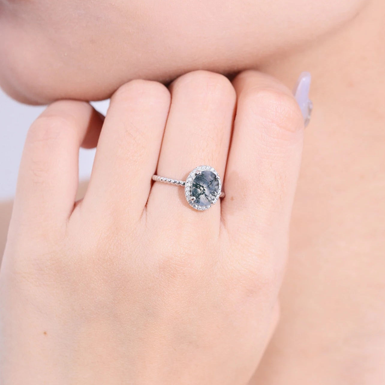 Close-up of a hand wearing a silver ring with a blue gemstone.