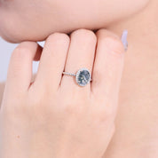 Close-up of a hand wearing a silver ring with a blue gemstone.