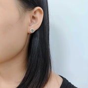 Close-up of a person wearing a green gemstone earring against a light background